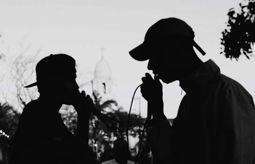 Dois artistas se apresentando com microfones em uma roda cultural